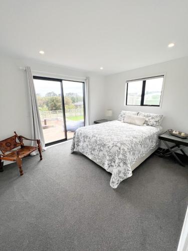 a white bedroom with a bed and a large window at Coastal Charm Escape in Karikari Peninsula
