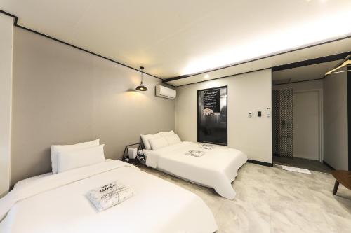 a room with two beds and a mirror at Fine Avenue Hotel in Changwon