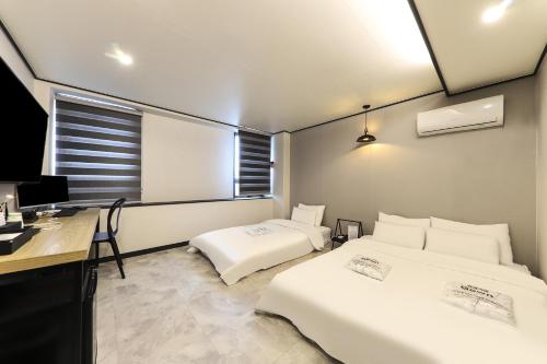 two beds in a room with a desk and a computer at Fine Avenue Hotel in Changwon