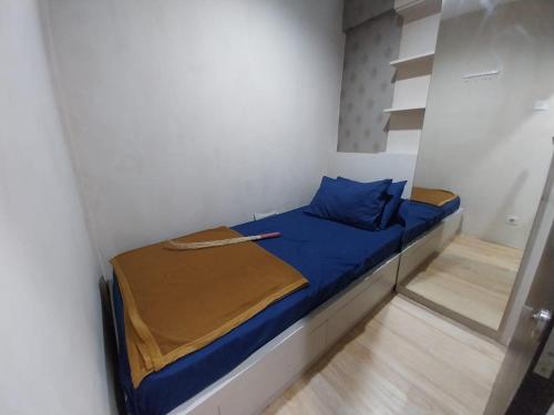 - un petit lit dans une petite chambre avec des draps bleus dans l'établissement Raja Apartemen Jarrdin Type 33, à Bandung