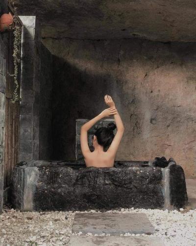 a shirtless man is sitting on a stone ledge at Hang Mua Ecolodge in Ninh Binh