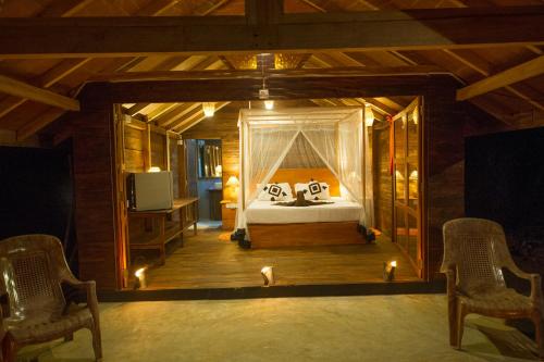 a bedroom with a bed in a room with chairs at 360 Rainforest in Deniyaya
