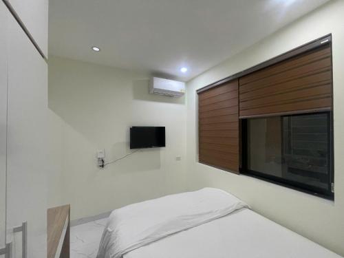 a bedroom with a large window and a tv on the wall at Era Apartment Xuân Thuỷ in Hanoi