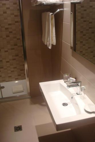 a bathroom with a white sink and a shower at Aegli Hotel Volos in Volos