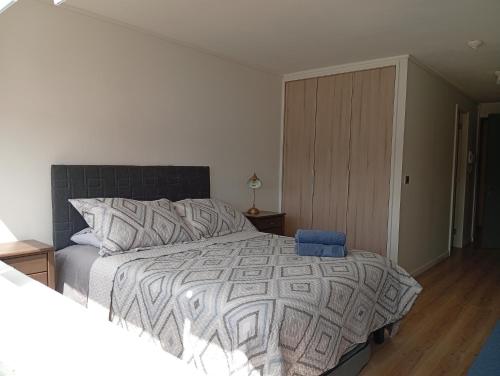 a bedroom with a large bed with a blue chair at Departamentos JM osorno in Osorno