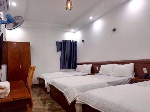 a hotel room with two beds and a table and a desk at Bảo Huy Hotel Tam Kỳ in Tam Ky