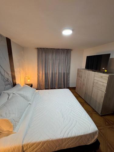 ein Schlafzimmer mit einem großen weißen Bett und einem Fernseher in der Unterkunft AlojamientoEl Doradoairport in Bogotá