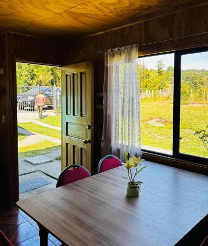 a table and chairs in a room with a large window at Cabañas Amanecer Sector Campo 1 in Castro