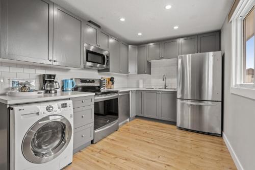 a kitchen with stainless steel appliances and a washer and dryer at Comfy, Cozy, Central Calgary, 2BR and 1BTH in Calgary