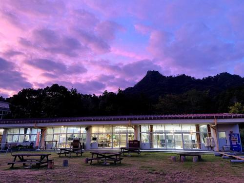 a building with picnic tables in front of a sunset at Heguri Hub in Minamiboso
