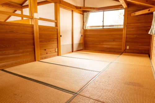 an empty room with wooden walls and a window at 閑乗寺JoyBase in Nanto