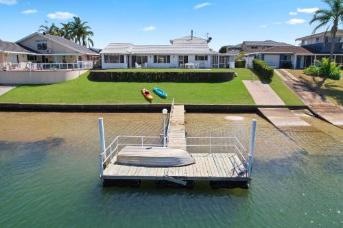 a boat sitting on the water in front of a house at Deja Bleu - great family home with jetty in Port Macquarie