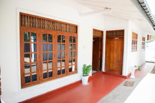 a porch of a house with wooden doors and a plant at Surf Hostel Hiriketiya in Dickwella