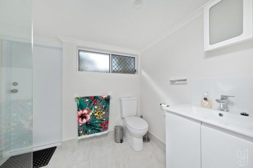 een witte badkamer met een toilet en een wastafel bij Serenity Cottage Beach Escape in Yeppoon