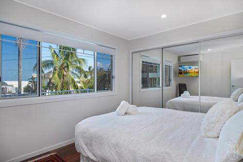 een slaapkamer met twee bedden en een groot raam bij Serenity Cottage Beach Escape in Yeppoon