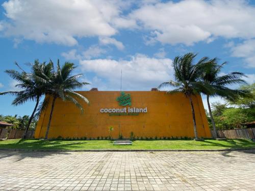 a large building with palm trees in front of it at Avery Coconut Island Waterpark Beach Resort Carita in Carita