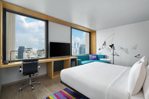 a hotel room with a bed and a desk and a tv at Aloft by Marriott Bangkok Sukhumvit 11 in Bangkok