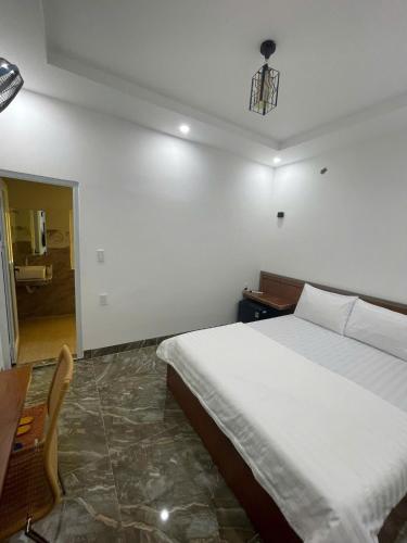 a bedroom with a large white bed and a chair at Bảo Huy Hotel Tam Kỳ in Tam Ky