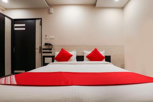 a bedroom with a large bed with red pillows at Hotel O Sr Residency in Vijayawāda