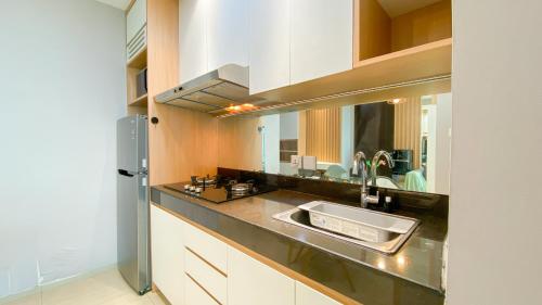 eine Küchentheke mit einem Waschbecken und einem Spiegel in der Unterkunft Fancy and Nice 1BR at Citralake Suites Apartment By Travelio in Jakarta