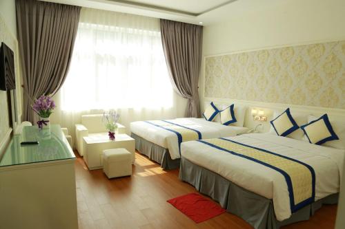 a hotel room with two beds and a window at White Hotel Nghệ An in Vinh