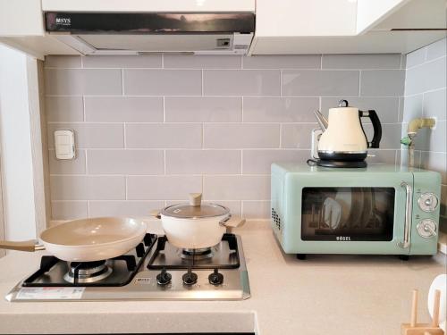 a kitchen with a stove with two pots and a microwave at Bongbong Stay in Seoul