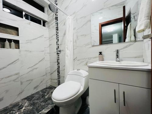 a white bathroom with a toilet and a sink at Andes Retreat 5 Bedroom 3 Bath in Baños