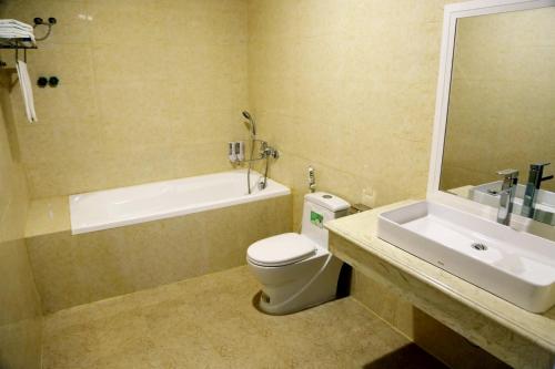 a bathroom with a sink and a toilet and a bath tub at White Hotel Nghệ An in Vinh