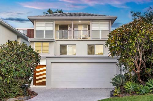 a white house with a white garage door at Pool side Luxury pet friendly - walk to the beach in Alexandra Headland