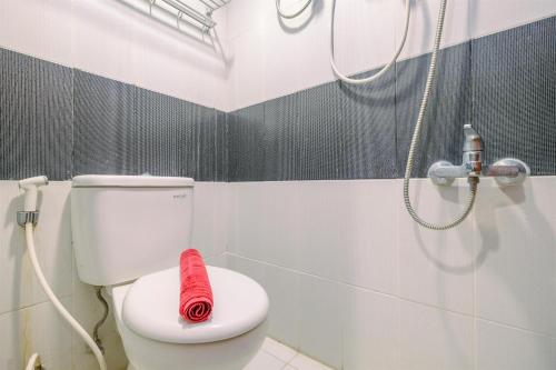 a bathroom with a toilet with a red towel on it at Classic and Cozy Studio at Cinere Bellevue Suites Apartment By Travelio in Depok