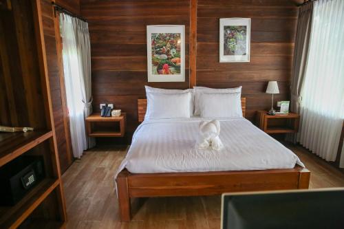 a white dog sitting on a bed in a bedroom at Avery Coconut Island Waterpark Beach Resort Carita in Carita