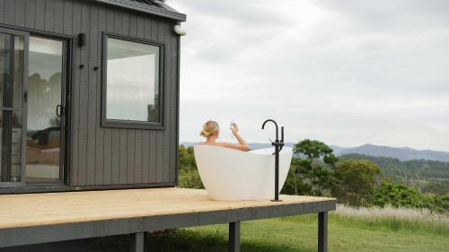 a woman sitting in a bath tub next to a house at Tiny Heidi in Imbil