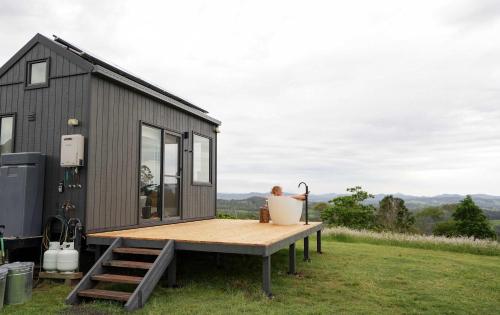 a black tiny house sitting on top of a field at Tiny Heidi in Imbil