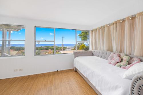 a living room with a white couch and large windows at Sun Catcher - ocean views, walk to beach, lake, cafés, shops in Lake Cathie
