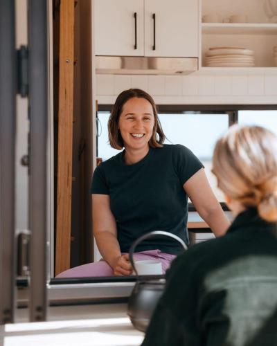 a woman is smiling while sitting in a kitchen at Tiny Lenore in Dunkeld