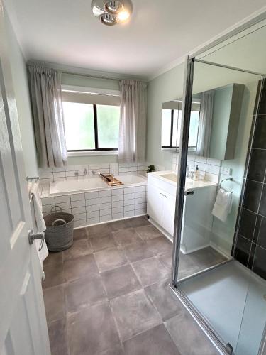 a bathroom with a tub and two sinks and a shower at Tranquil, modern self-contained cottage in Scarsdale