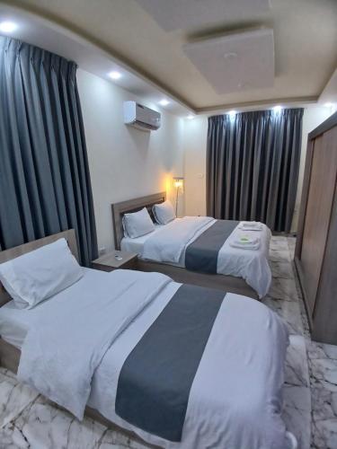 two beds in a hotel room with curtains at dream house hotel in Jerash