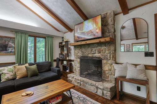 a living room with a couch and a stone fireplace at Treetop Hideaway - Summer Escape with HOT TUB in Gatlinburg