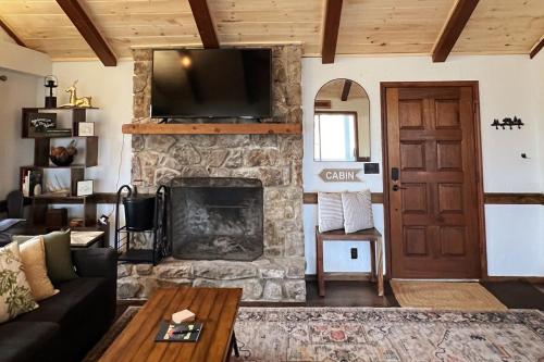 a living room with a stone fireplace with a television at Treetop Hideaway - Summer Escape with HOT TUB in Gatlinburg