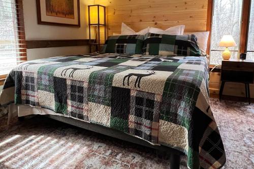 a bedroom with a bed with a green and black blanket at Treetop Hideaway - Summer Escape with HOT TUB in Gatlinburg