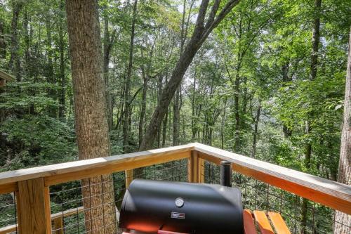 a chair on a deck with a view of the woods at Treetop Hideaway - Summer Escape with HOT TUB in Gatlinburg