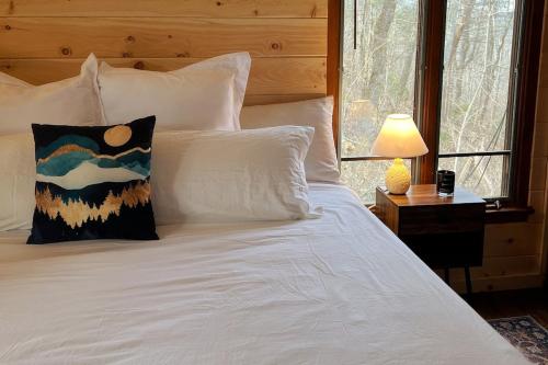 a bed with white pillows and a table with a lamp at Treetop Hideaway - Summer Escape with HOT TUB in Gatlinburg