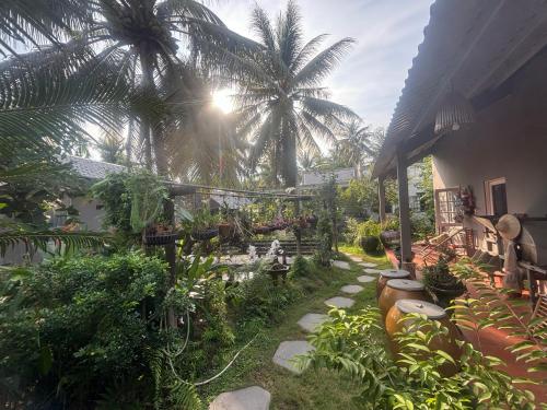a garden with palm trees and a house at Homestay Bentre Coco Lodge in Ben Tre