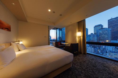 a hotel room with a large bed and a large window at JR Kyushu Hotel Blossom Shinjuku in Tokyo