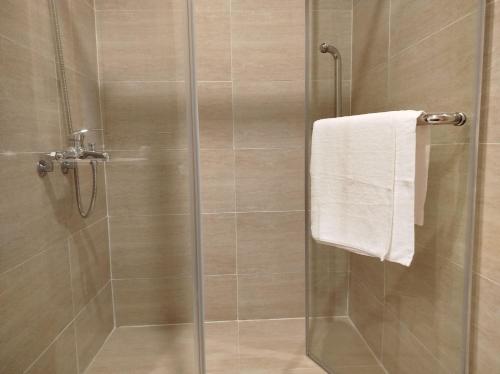 a shower with a glass door and a towel at Queen HT Phú Quốc in Phu Quoc