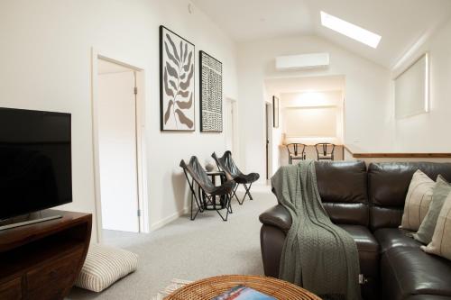 a living room with a brown leather couch and chairs at Athlete's Retreat - 21A Service Street in Porepunkah