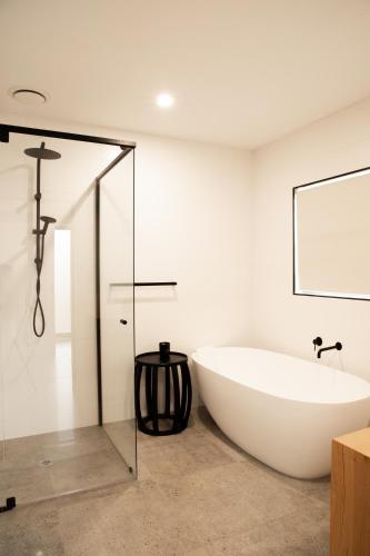 a bath tub in a bathroom with a glass door at Athlete's Retreat - 21A Service Street in Porepunkah