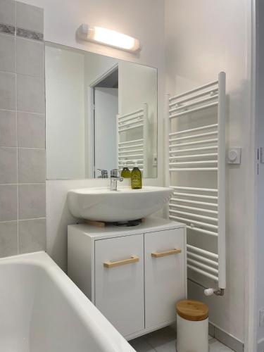 La salle de bains blanche est pourvue d'un lavabo et d'une baignoire. dans l'établissement 5 min Versailles & Golf National, à Guyancourt