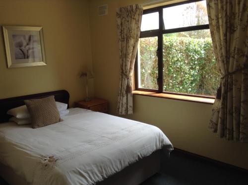 Schlafzimmer mit einem Bett und einem Fenster in der Unterkunft Riverlodge Self Catering in Kenmare
