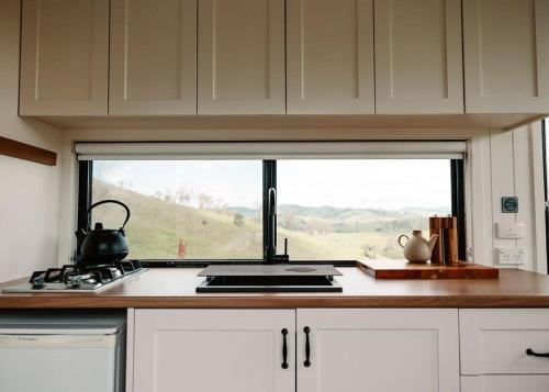 una cocina con una ventana sobre una estufa y una barra en Tiny Mowgli, en Bulliac